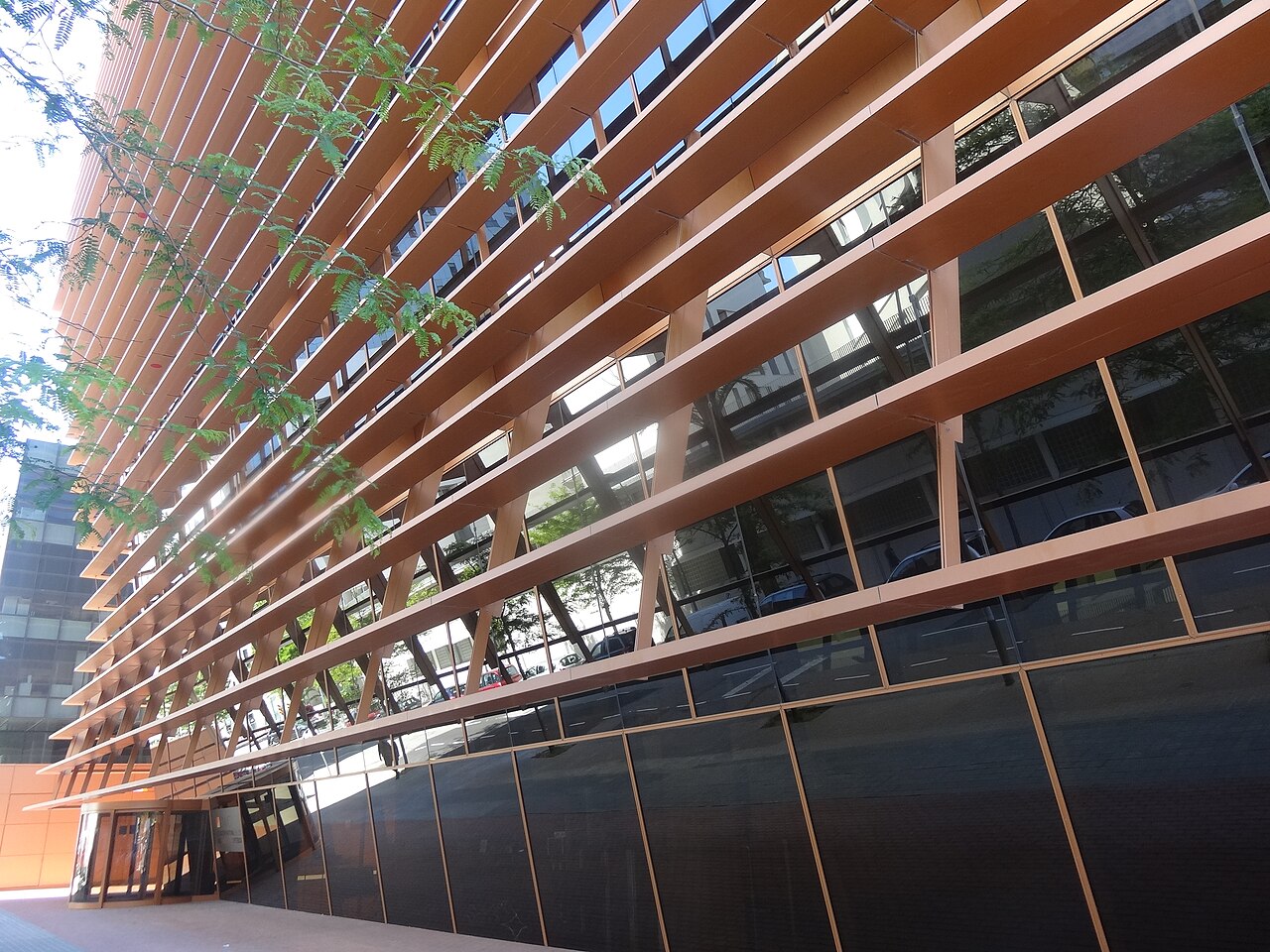 Fachada del edificio de la Comisión Nacional de los Mercados y la Competencia en Barcelona, con lamas horizontales de color cobre sobre los ventanales