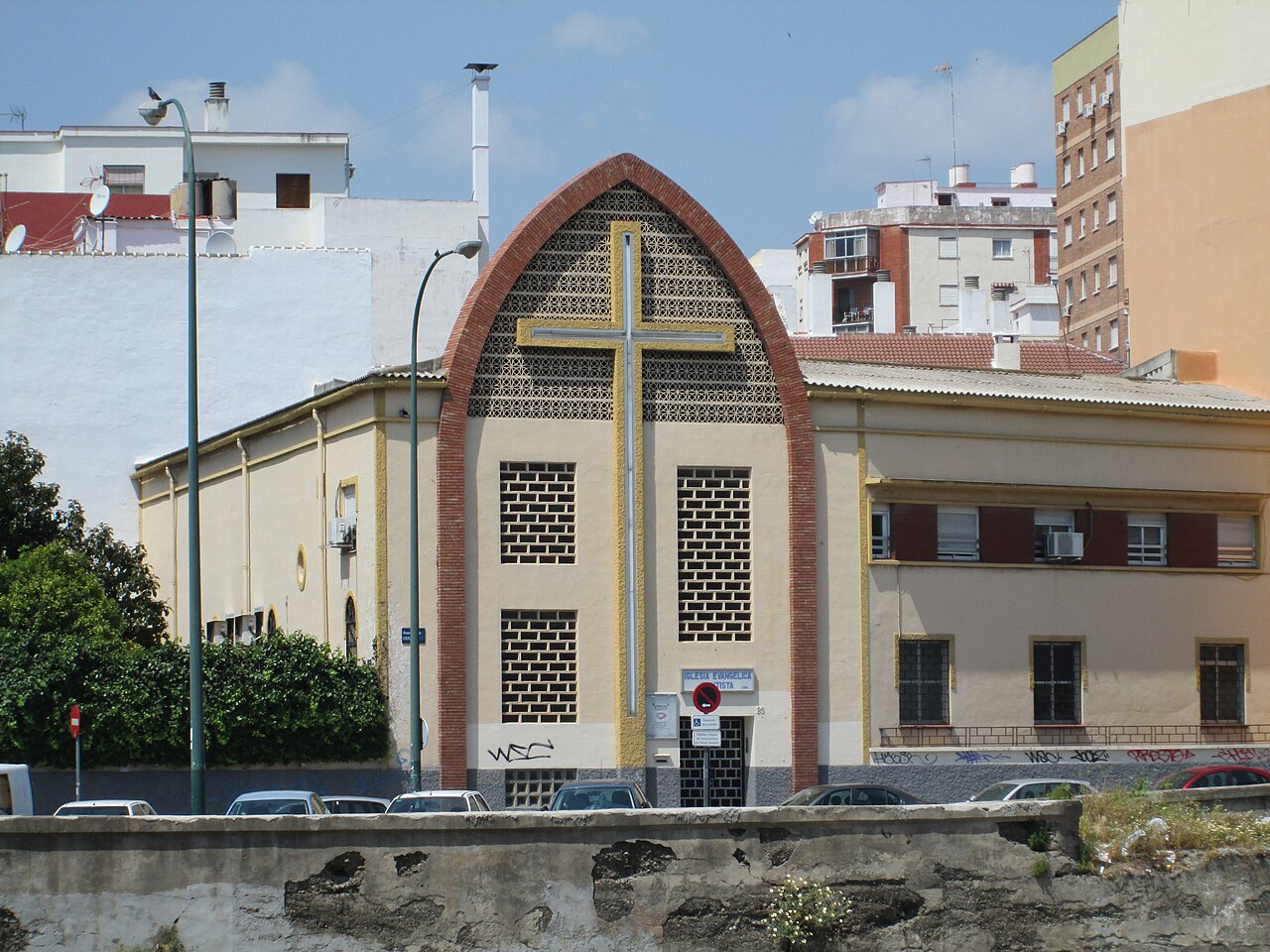 Fachada de un templo de la Iglesia Evangélica Bautista en Málaga, edificio de ladrillo claro con puerta de acceso a pie de calle