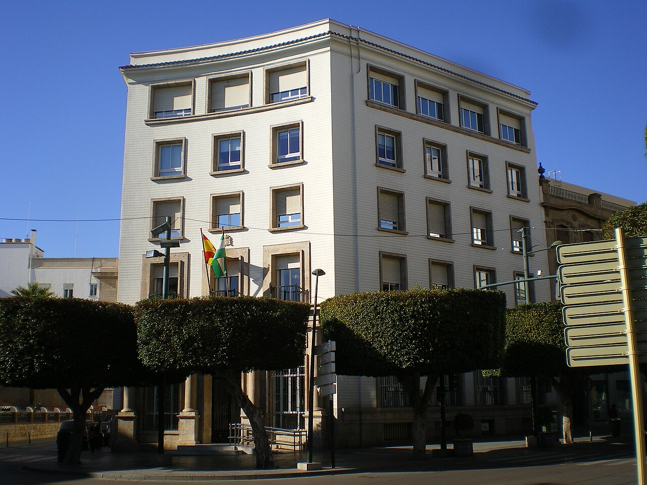 Edificio de la Dirección Provincial del Instituto Nacional de la Seguridad Social en Almería, de fachada blanca y cinco alturas, con las banderas de España y de Andalucía sobre la entrada