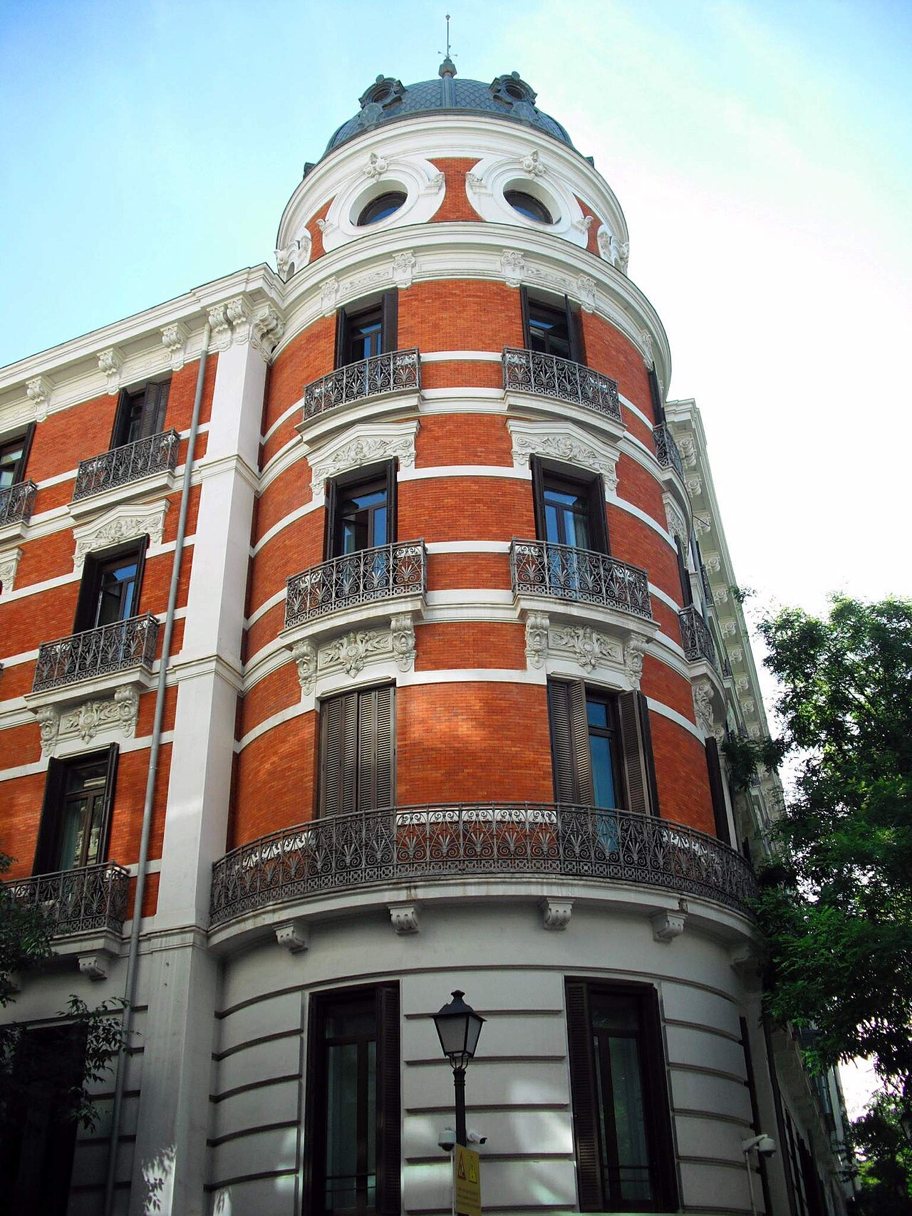 Esquina de un edificio de ladrillo rojo y piedra blanca con torreón y cúpula, sede del Ministerio del Interior en la calle Amador de los Ríos de Madrid